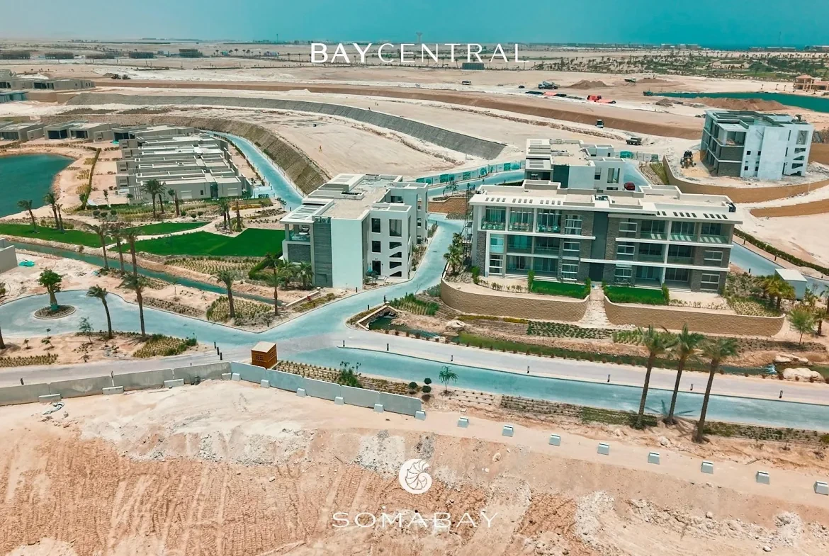 سوما باي، باي سنترال — لقطة جوية لمبانٍ سكنية منخفضة الارتفاع ومساحات خضراء وواجهة بحيرة على ساحل البحر الأحمر